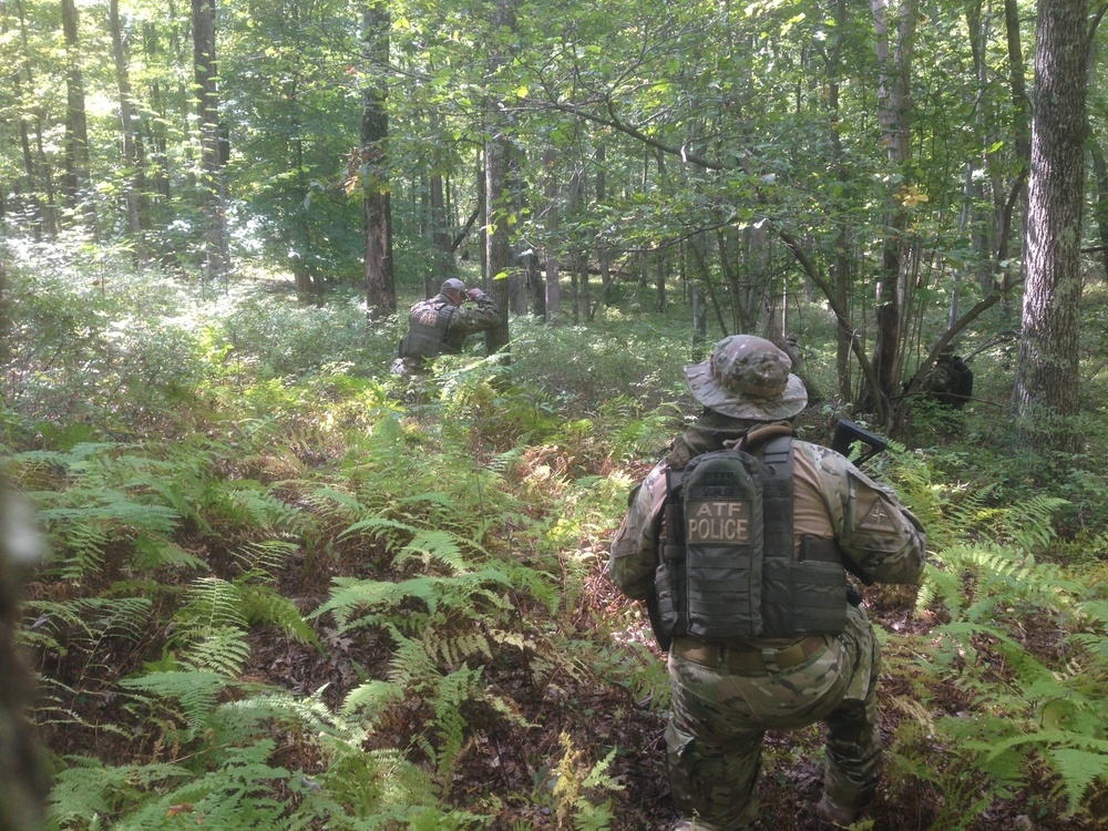 ATF Special Response Team members searching wooded terrain in tactical gear